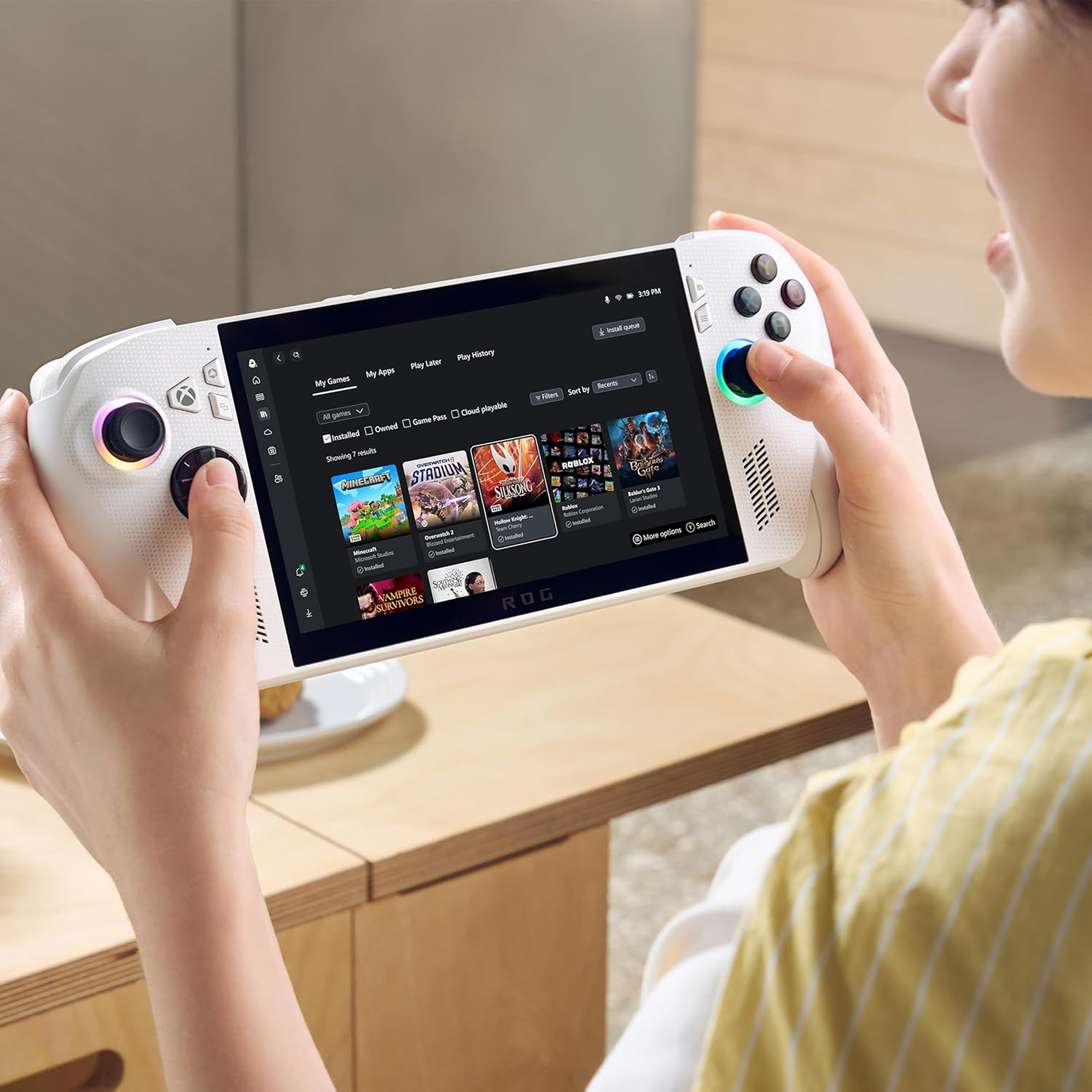 Person holding a gaming console with a screen displaying game options